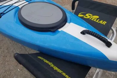 Blue and white Stellar kayak with seat and storage hatch.