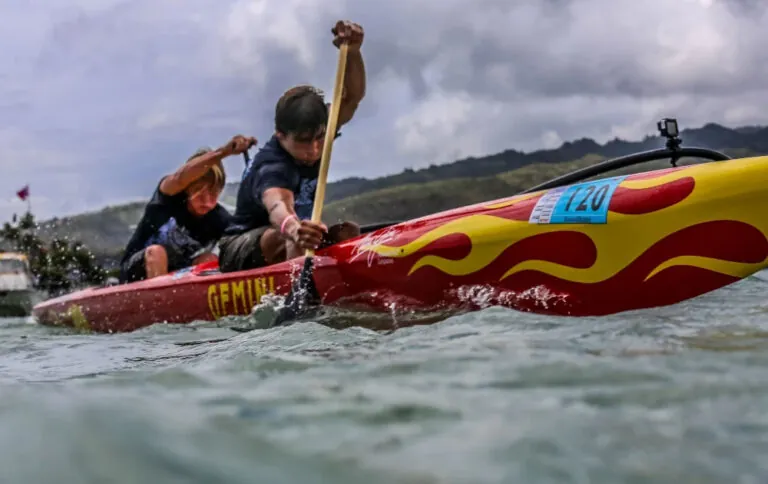 Two people paddling a red kayak in choppy waters