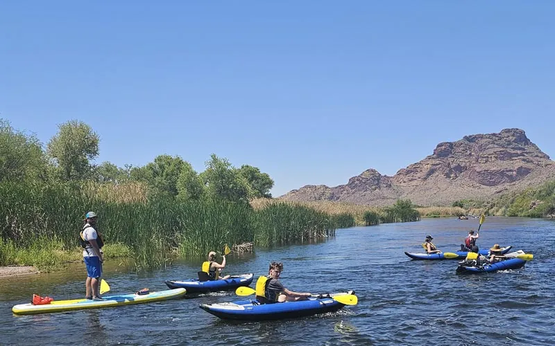 People paddleboarding and kayaking on the Lower Salt River with a mountain backdrop on a Riverbound Sports guided tour